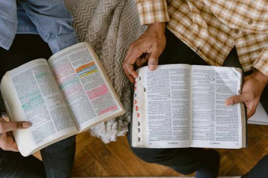People sitting together and holding open Bibles for their Bible study