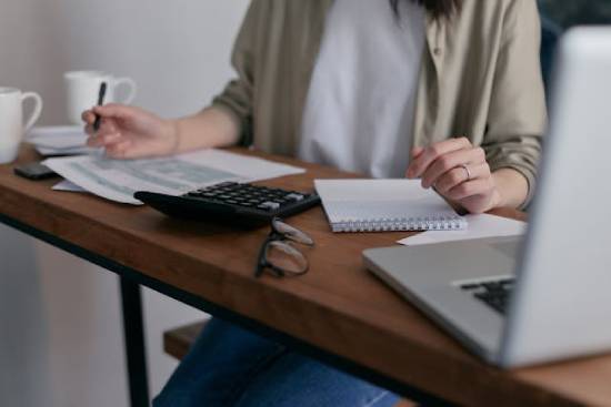 Woman Calculating how Much Debt she has to Repay The image of a woman calculating her debts reminds us that the Bible guides us to repay all we owe in a timely manner.