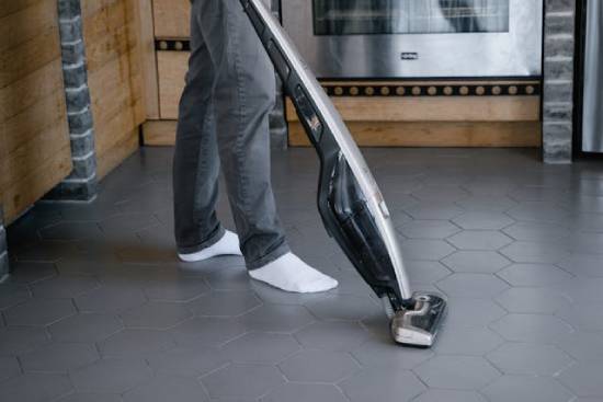 A man vacuuming his kitchen floor.