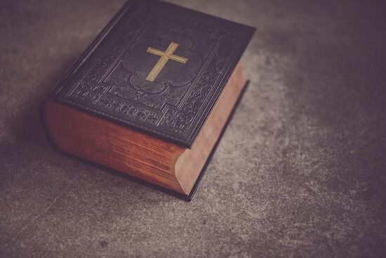 A Bible with reddish edges and a golden cross on the front