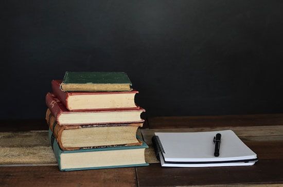 A stack of books A stack of books, notebook, and a pen for Bible study