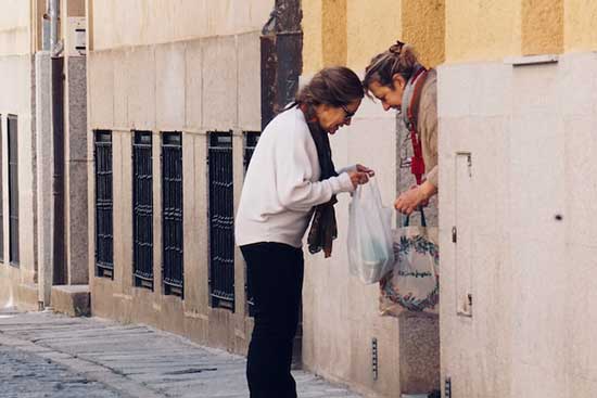 Woman giving another a bag Adventist Christians applying the Bible by serving and distributing food to others