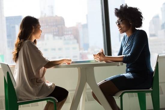 Two women sitting across from each other at a table Two women sitting across from each other at a table, illustrating the importance of communication in a relationship just like prayer is our communication with God