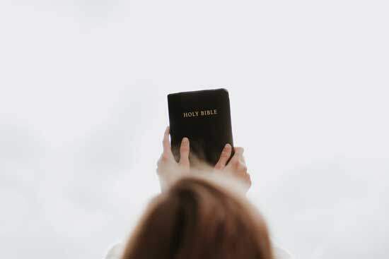 A woman holding a Bible up to the sky.