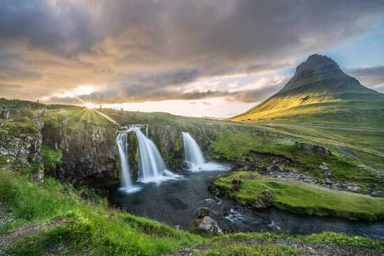 Waterfalls running near Kirkjufell Mountain on a sunny and cloudy day are an example of Creation's beauty.