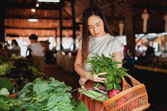 Woman buying fresh produce in a market Getting fresh produce from a local market is a great way to enhance nutrition!