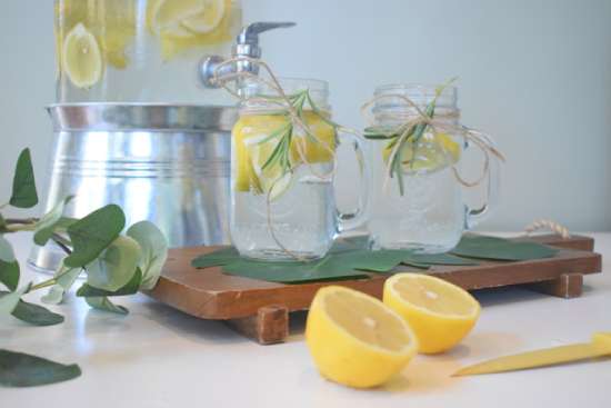 Lemon water in jars Two pitchers with lemon water, and a lemon cut in half on the table.