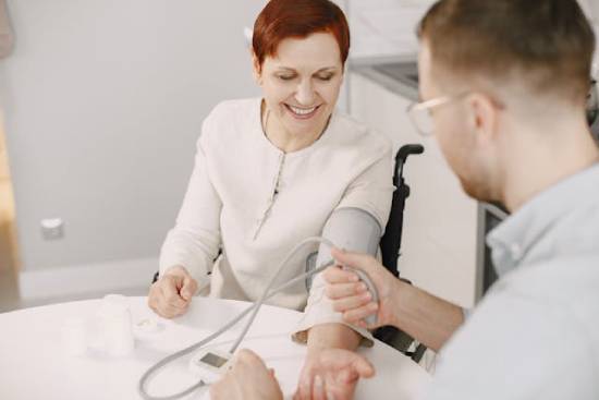 A doctor takes a woman's blood pressure, illustrating how lower blood pressure is one of the benefits of the vegetarian diet.