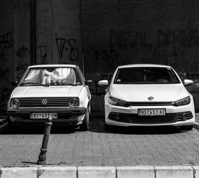 One old car and one new car side by side An older and newer car of the same brand parked next to each other.