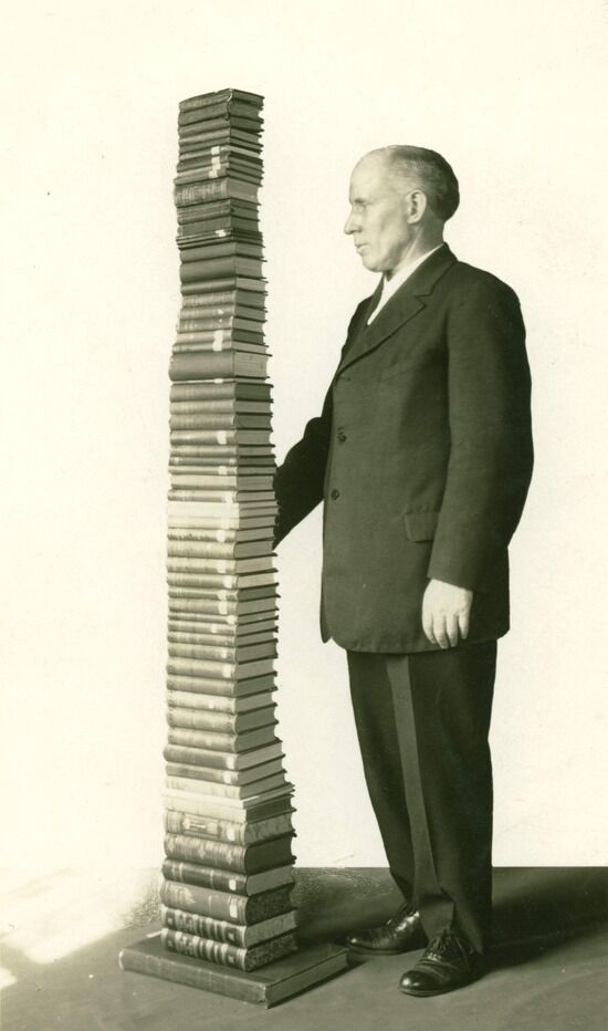 Stack of Ellen White's books A man standing next to a stack of Ellen White's books