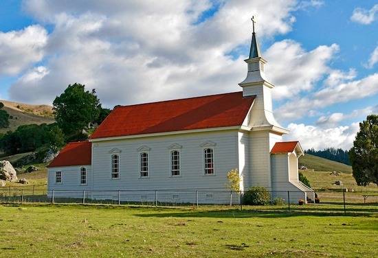 A small country church surrounded by fields.