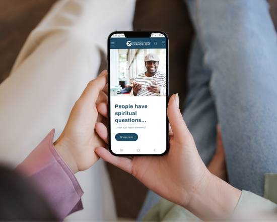Two people hold a smartphone between them and look at the Center for Online Evangelism store.