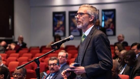 A church member speaks into a microphone at a meeting, illustrating how ordinary Adventists have a voice in the church.