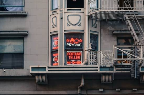 Window advertising psychic and fortune teller services with neon signs Neon signs in a window advertising a fortune-telling business
