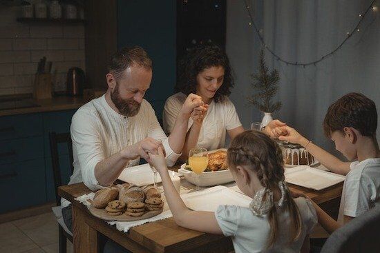 Praying Over Meal An Adventist family holding hands as they pray over a meal