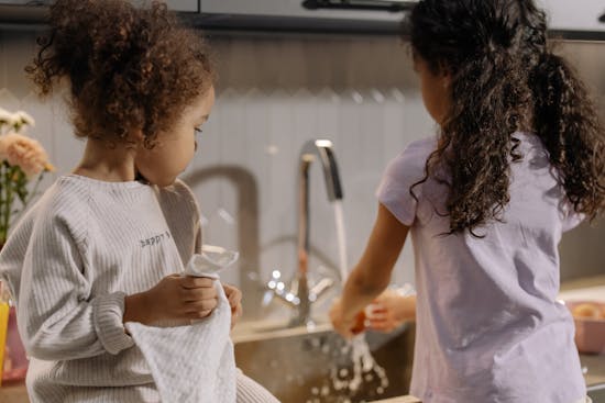 Two little girls helping to wash and dry dishes Two sisters washing and drying the dishes, which helps keeps the house clean and neat