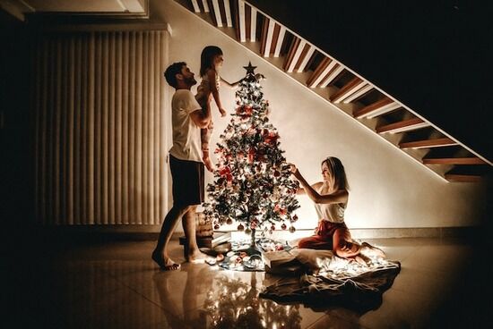 Family Decorating Tree A mother, father, and daughter decorating a Christmas tree by candlelight