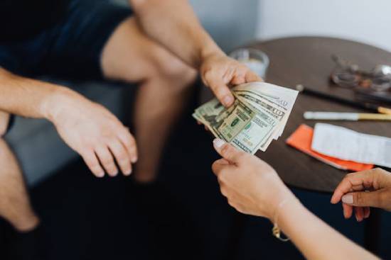 Person Lending Money to Someone Else The image of someone handing money to another person reminds us to follow the Bible's principles for lending.
