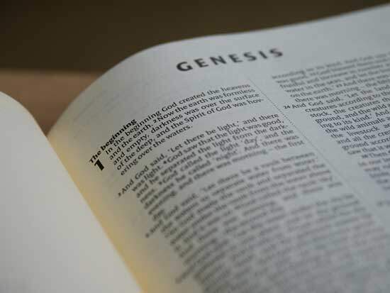 A Bible open to Genesis 1, where the Creation story is documented.