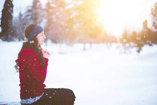 Woman praying A woman kneeling in the snow and praying as she seeks spiritual growth