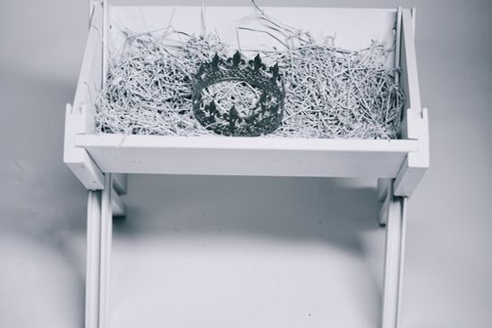 A king's crown resting inside a manger on a bed of hay