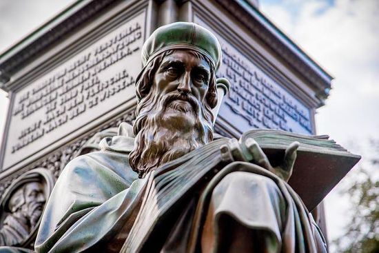 A sculpture of John Wycliffe reading the Bible A statue of John Wycliffe, who completed the first English Bible translation.