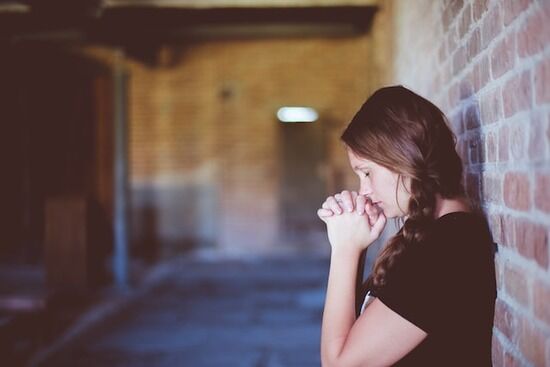 Women Praying at Wall A woman prays to Jesus in a hallway