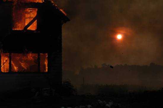 Burning house with red sun in the background A house burning in the dark illustrates some of the chaos many think about when they hear about the