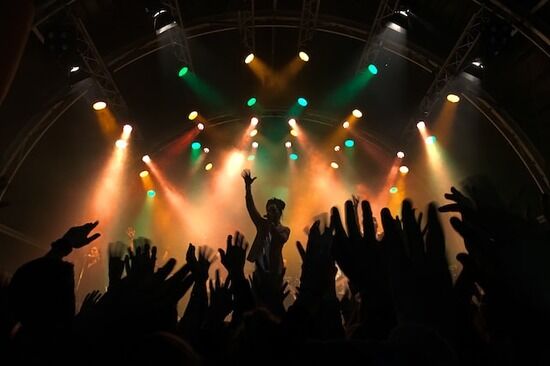 Musical concert People raising their hands for a music artist, symbolizing the human tendency to idolize and worship other humans