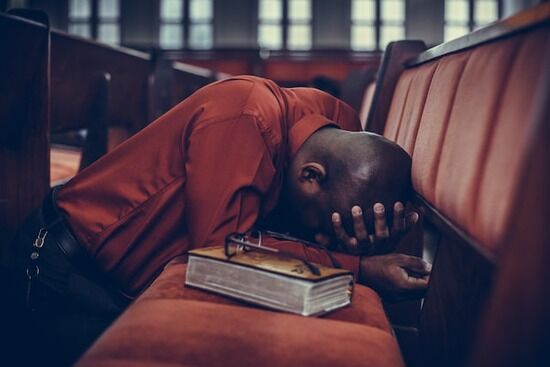 Prayer at Church Man kneeling down at a Church pew, earnestly praying as we explore what is the importance of prayer in our lives