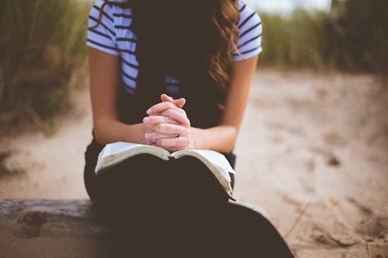 Girl in prayer A girl reading a devotional and praying