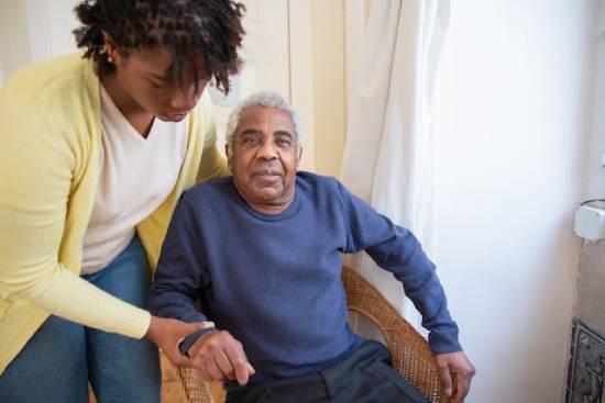 Helping an elderly man A woman helps an elderly man in a chair, representing how selflessness can help us develop fruits of the Spirit.