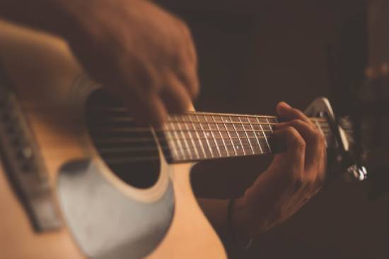 Man playing a guitar A man playing guitar. Guitars are one way we arrange tones, melodies, and rhythms.