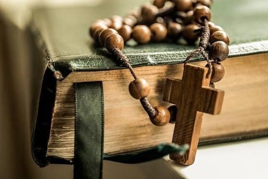Rosary on Catholic Bible An old Greek Bible open on top of a notebook