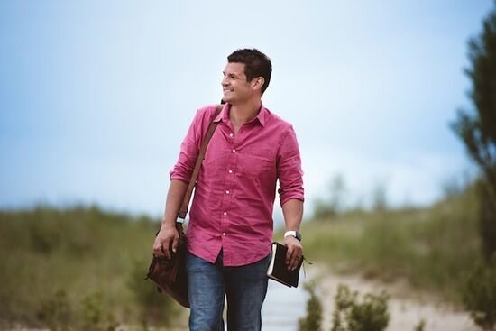 Smiling Man Carrying Bible A man walking with a Bible in his hand