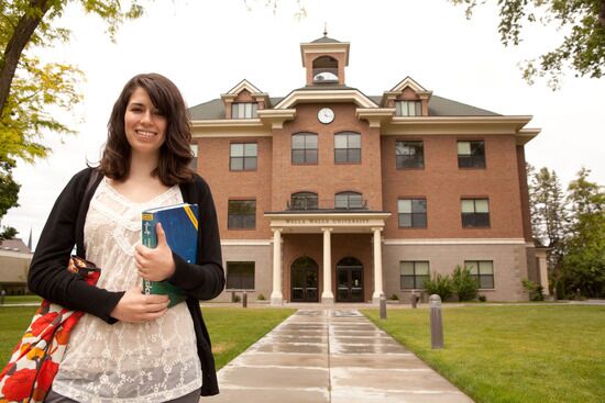 Student Outside Walla Walla University A young woman holding books and standing outside a building at Walla Walla University