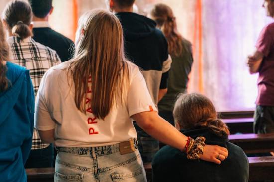 Woman gives emotional support to her friend in church A woman stands with her hand on her friend's back, illustrating a supportive environment in church, which is so refreshing when embarking on a spiritual journey.