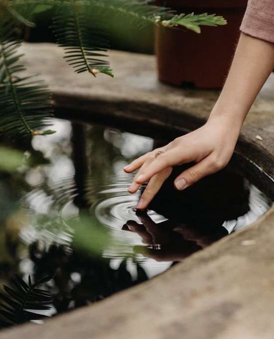 Unrecognizable woman touching water in well A woman touching a finger to a pool of still water