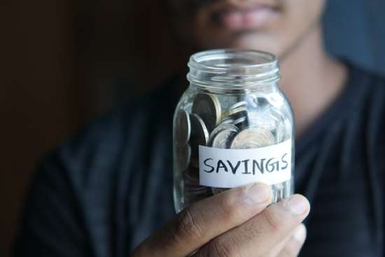 Coins in a Savings Jar A person holding a jar of coins as part of their savings.