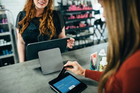 Woman Buying Items in a Store A woman at the store, paying for her items with a credit card.