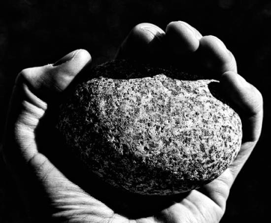A hand holding a large stone A close up of a hand holding a large stone.