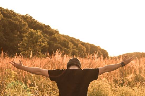 Man in a field with arms outstretched worshipping God A man in a field with his hands outstretched in worship