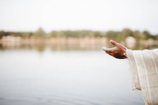 Hand of Jesus outstretched in an offer of salvation A robed arm opens wide with a river in the background.