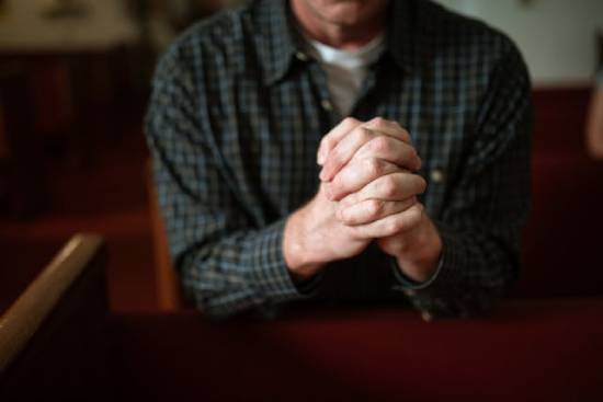 A man praying for the Holy Spirit A man prays with his hands clasped together in prayer