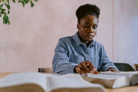 Woman studying the Bible A Black young woman sits at a table and studies the Bible.