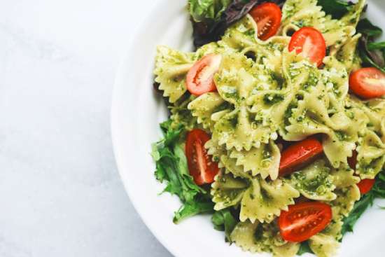 Pesto Pasta A white plate with pesto pasta and tomatoes