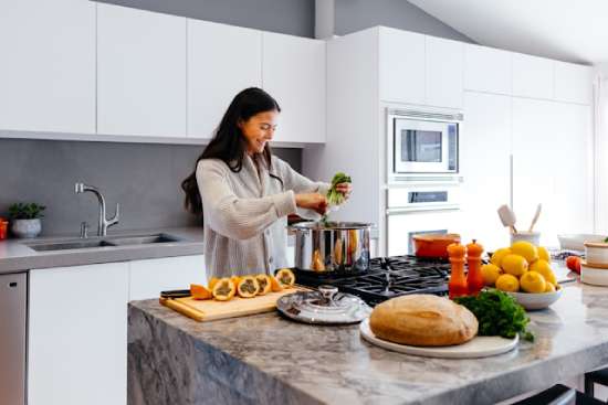 A Woman Cooking Healthy Food A woman cooking healthy food in her kitchen and smiling