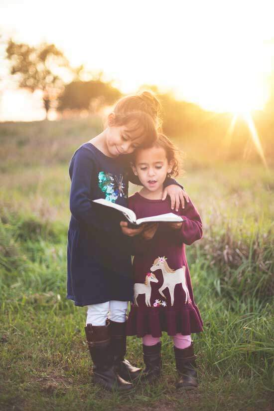Two young sisters read the Bible together.