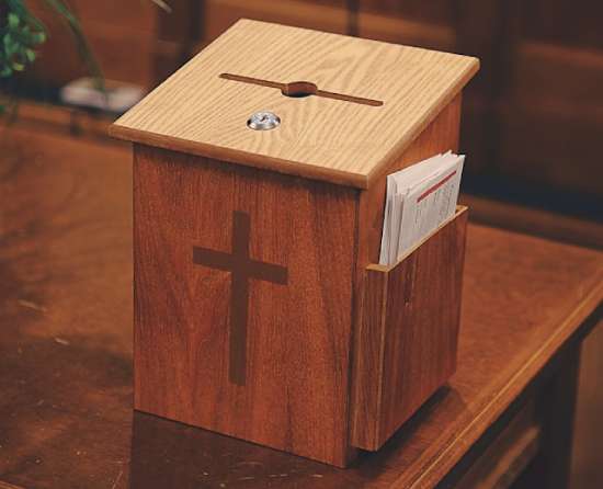 Wooden box with a cross in front and an opening on top holding tithe envelopes.
