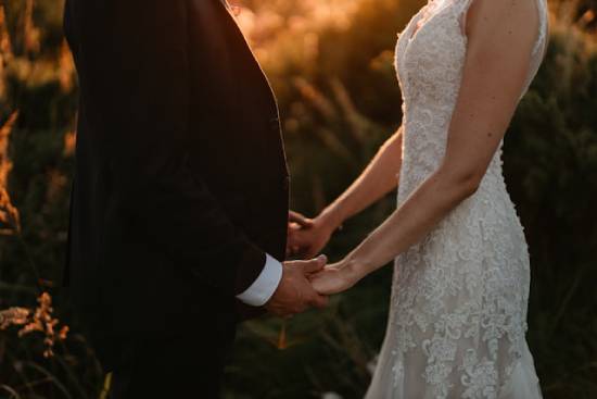 A bride and groom face each other and hold hands, depicting oneness in a marriage.